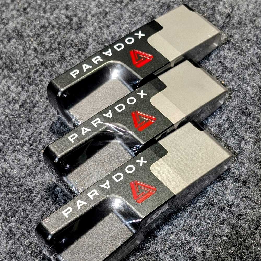 Three paradox putters stacked on a textured surface