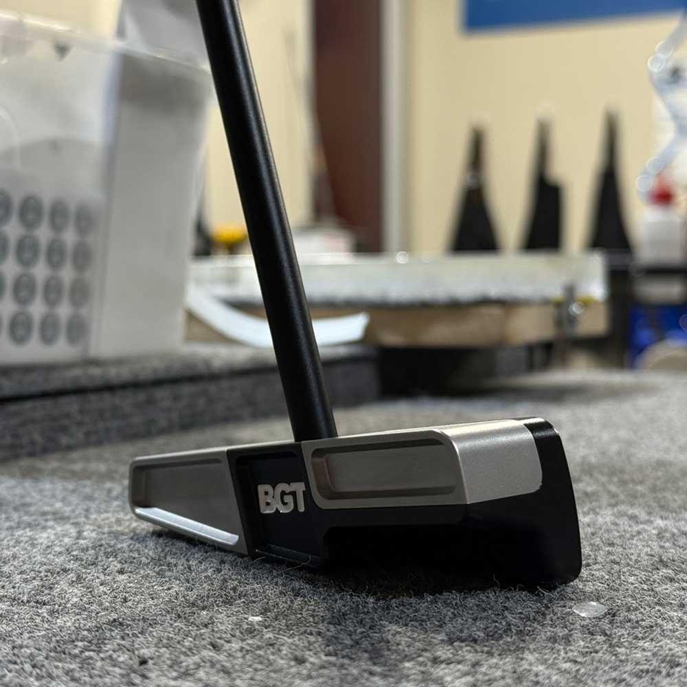 Golf putter with BGT logo on a gray surface