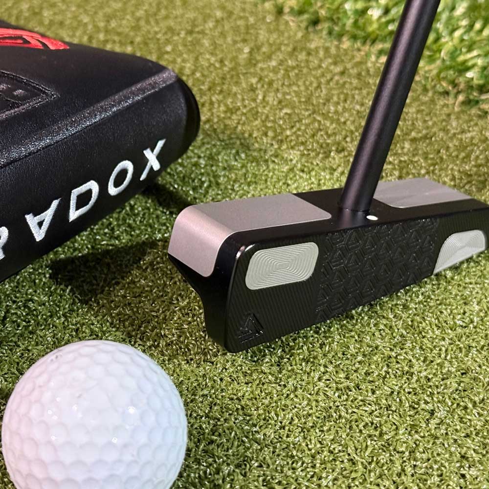BGT Paradox Putter, golf ball, and Odyssey putter case on a grass surface